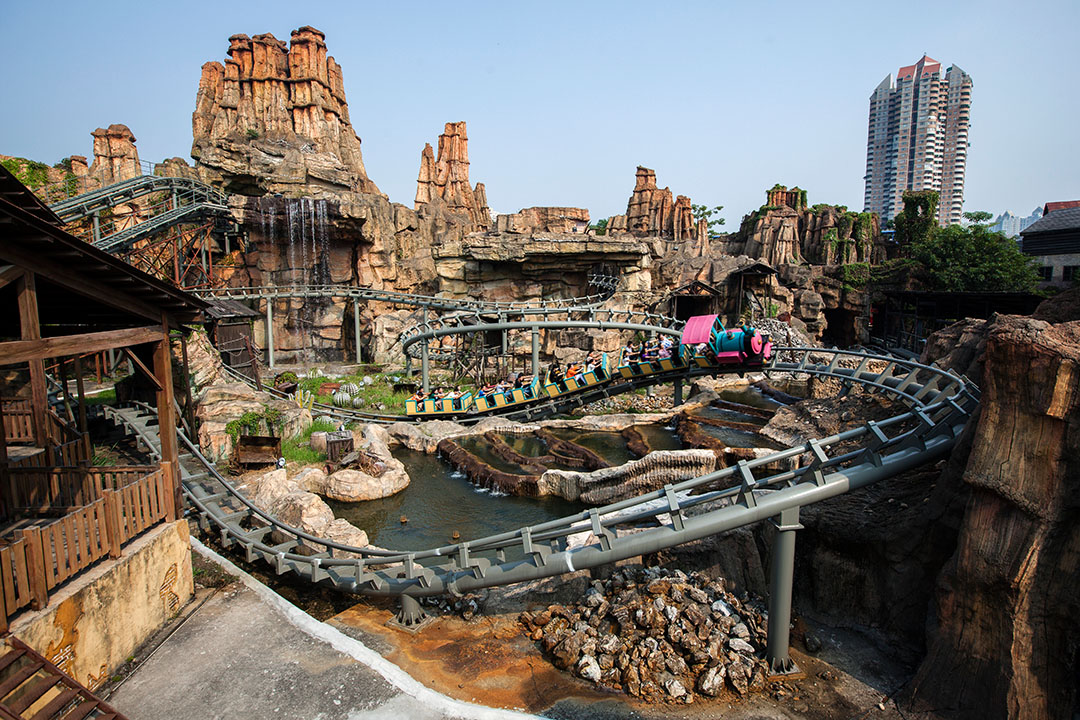 A rollercoaster twists through a faux goldmine in Happy Valley theme park. - Shenzhen, China
